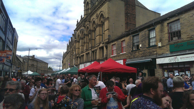 A large crowd of people donning sunglasses in the North Parade amongst food stalls